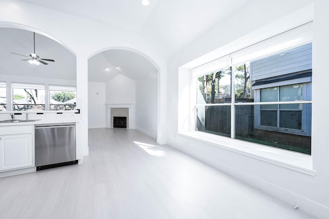 kitchen with a wealth of natural light, dishwasher, white cabinets, and vaulted ceiling