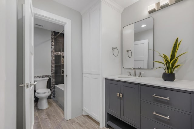 bathroom featuring hardwood / wood-style flooring, vanity, toilet, and tiled shower