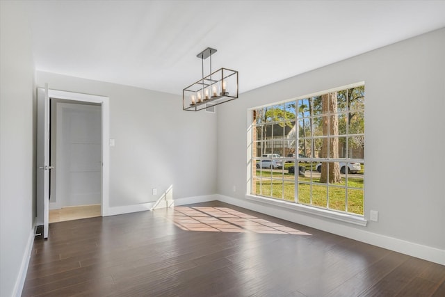 unfurnished dining area with a wealth of natural light, dark hardwood / wood-style flooring, and an inviting chandelier