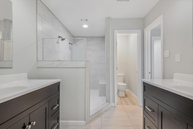 bathroom with hardwood / wood-style flooring, toilet, vanity, and tiled shower