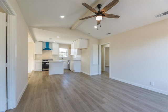 kitchen featuring light hardwood / wood-style flooring, vaulted ceiling with beams, wall chimney exhaust hood, white cabinetry, and stainless steel appliances