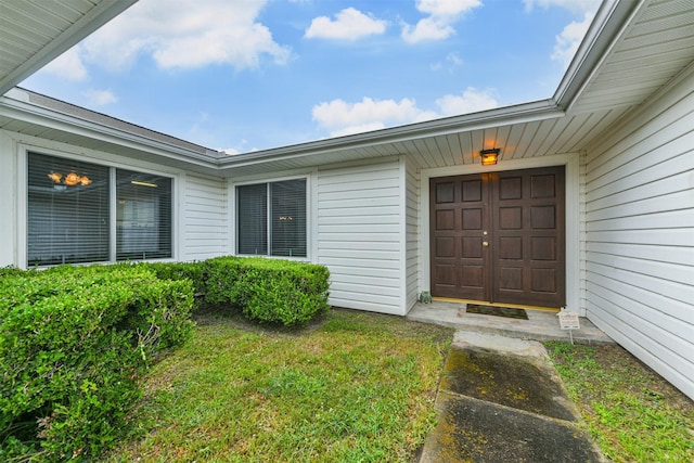 view of exterior entry featuring a lawn