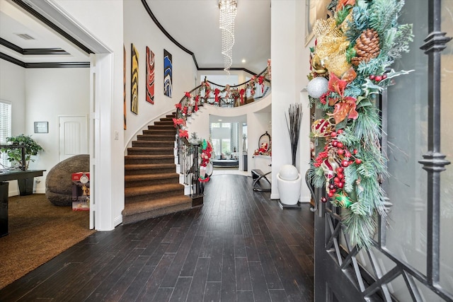 foyer with wood-type flooring, ornamental molding, and a towering ceiling