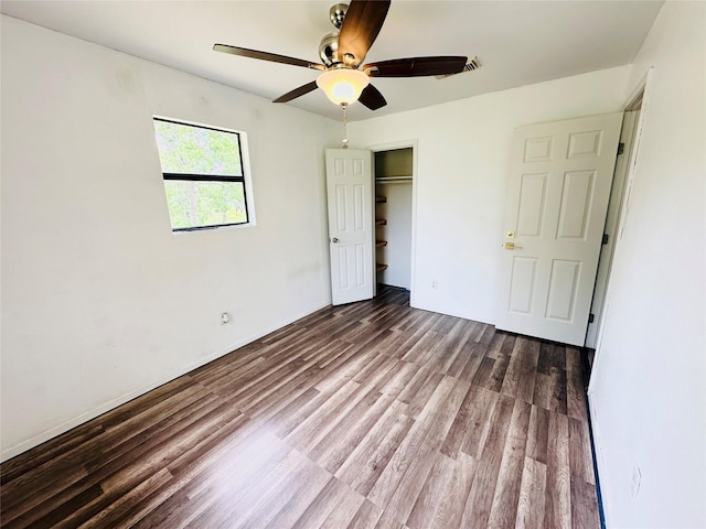 unfurnished bedroom with ceiling fan, dark wood-type flooring, and a closet