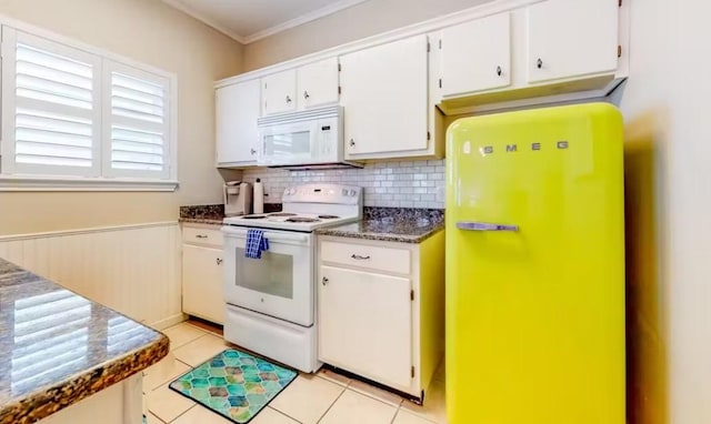 kitchen featuring white cabinets, dark stone countertops, crown molding, white appliances, and light tile patterned floors