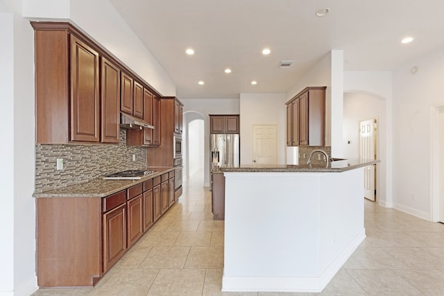 kitchen featuring stone counters, stainless steel appliances, kitchen peninsula, decorative backsplash, and light tile patterned floors