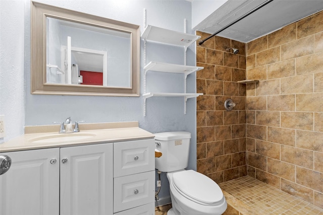 bathroom featuring vanity, toilet, and a tile shower