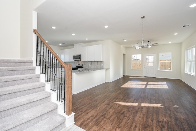 unfurnished living room featuring dark hardwood / wood-style flooring and ceiling fan with notable chandelier