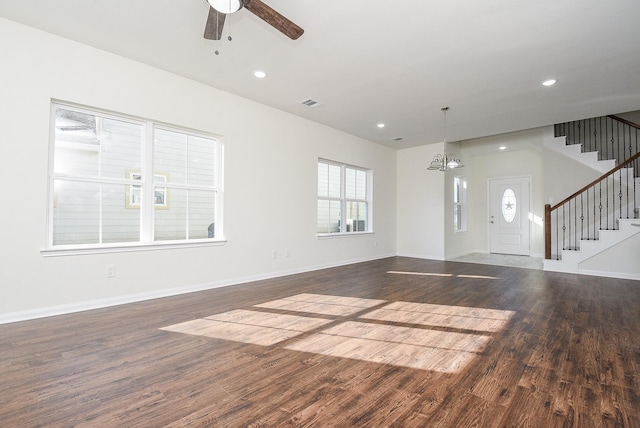 unfurnished living room featuring ceiling fan with notable chandelier and dark hardwood / wood-style floors