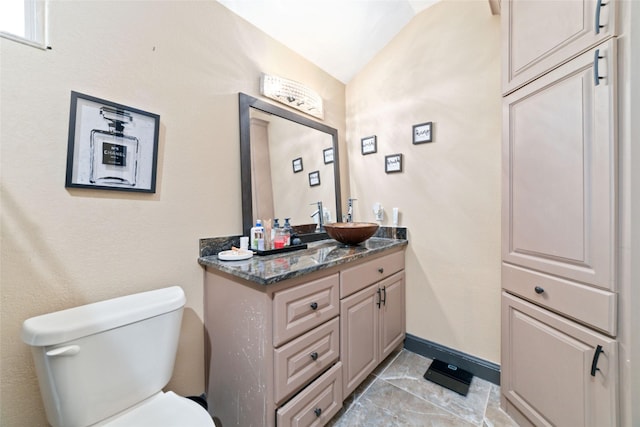 bathroom featuring vanity, vaulted ceiling, and toilet