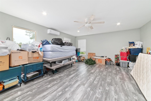 bedroom featuring a wall mounted air conditioner, light hardwood / wood-style floors, and ceiling fan