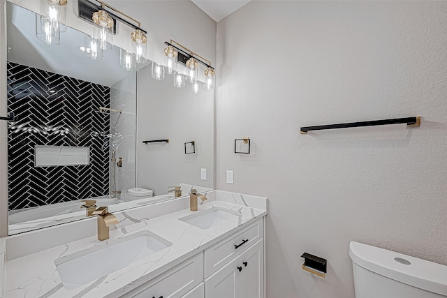 bathroom with tiled shower, vanity, and toilet