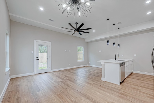 kitchen featuring dishwasher, light wood-type flooring, decorative light fixtures, and a wealth of natural light