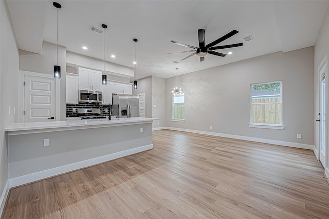 kitchen featuring white cabinets, pendant lighting, stainless steel appliances, and a wealth of natural light