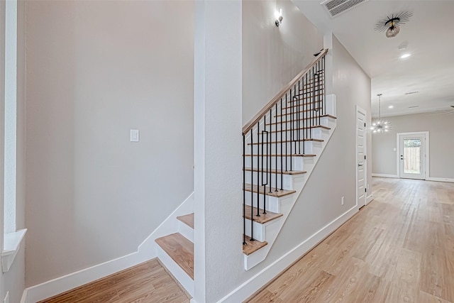 staircase with a chandelier and hardwood / wood-style flooring