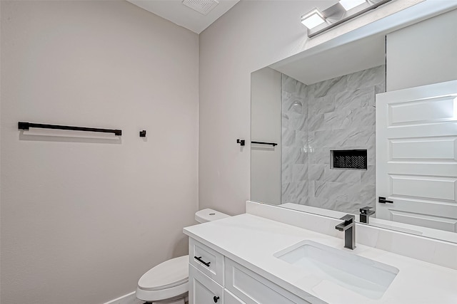 bathroom featuring a tile shower, vanity, and toilet