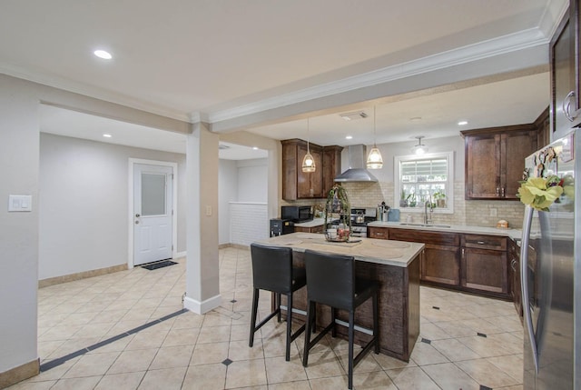 kitchen featuring a center island, sink, wall chimney exhaust hood, ornamental molding, and stainless steel appliances