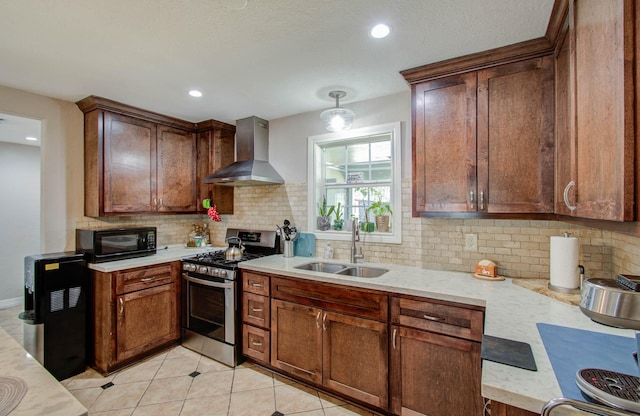 kitchen with sink, wall chimney range hood, stainless steel gas range, decorative backsplash, and light tile patterned floors