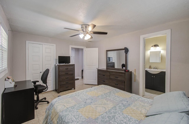 tiled bedroom featuring sink, ceiling fan, a textured ceiling, connected bathroom, and a closet