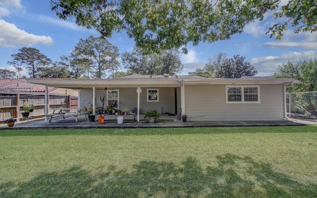 rear view of house featuring ceiling fan, a yard, and a patio