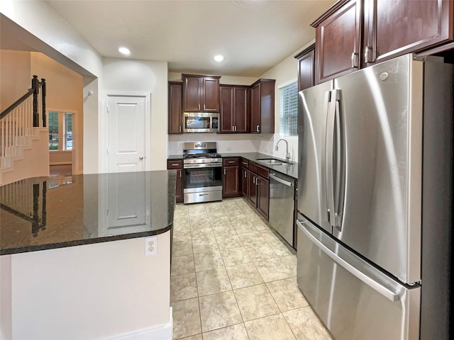 kitchen featuring light tile patterned floors, sink, stainless steel appliances, and dark stone countertops