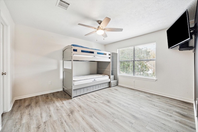 unfurnished bedroom featuring ceiling fan, light hardwood / wood-style floors, and a textured ceiling