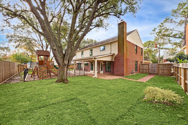 rear view of house with a yard and a playground