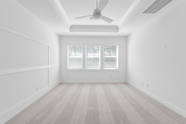 carpeted spare room with ceiling fan and a raised ceiling