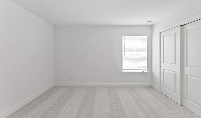 unfurnished bedroom with light colored carpet and a closet