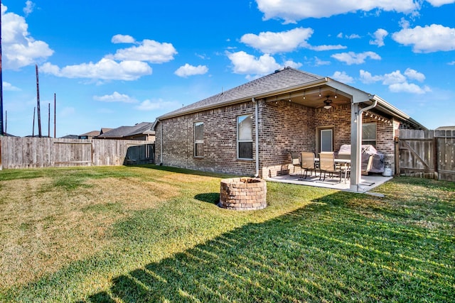 rear view of property with a fire pit, ceiling fan, a patio area, and a lawn