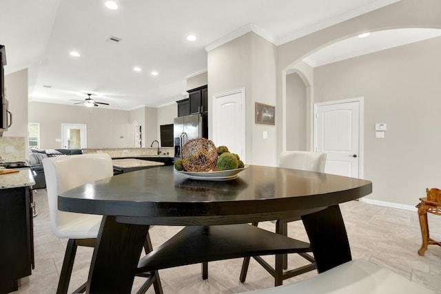 dining space featuring ceiling fan, sink, and crown molding