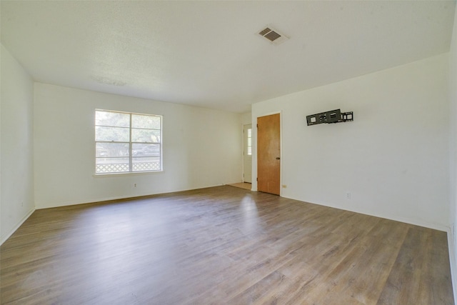 unfurnished room featuring a textured ceiling and light hardwood / wood-style flooring