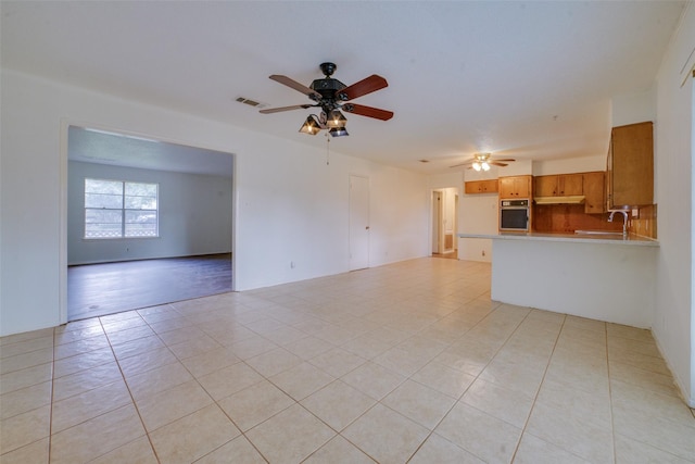 unfurnished living room featuring light tile patterned floors, ceiling fan, and sink