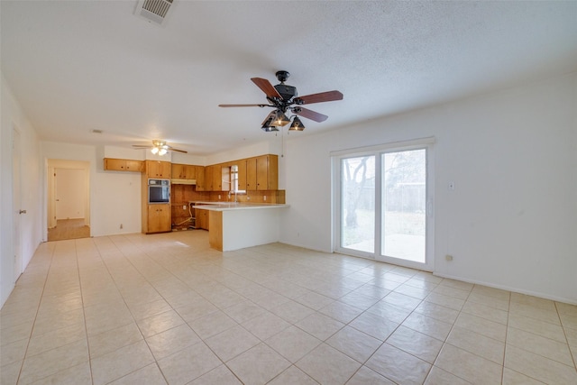 unfurnished living room featuring ceiling fan, sink, light tile patterned flooring, and a textured ceiling