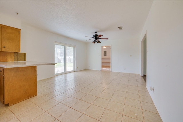 unfurnished living room featuring ceiling fan, light tile patterned floors, and a textured ceiling