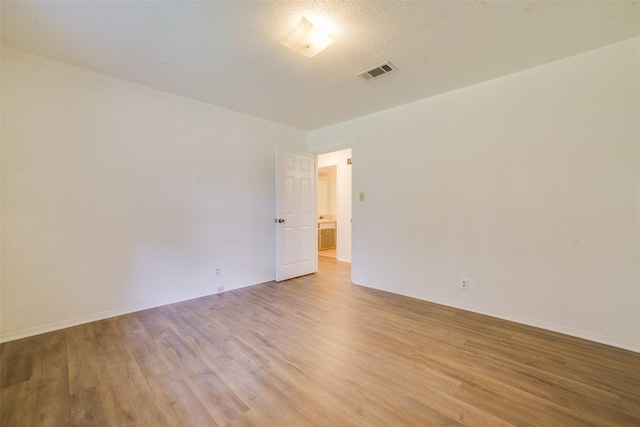 empty room featuring a textured ceiling and light hardwood / wood-style flooring