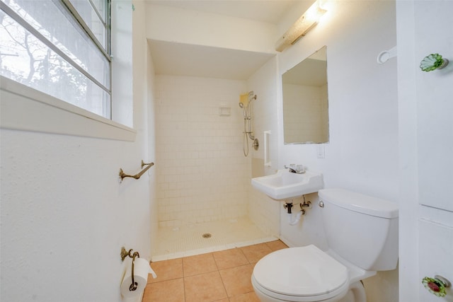 bathroom featuring tile patterned floors, sink, toilet, and tiled shower