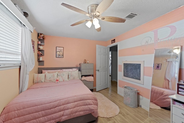 bedroom featuring ceiling fan, light hardwood / wood-style flooring, and a textured ceiling