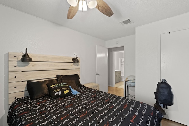 bedroom with hardwood / wood-style floors, ceiling fan, and a textured ceiling