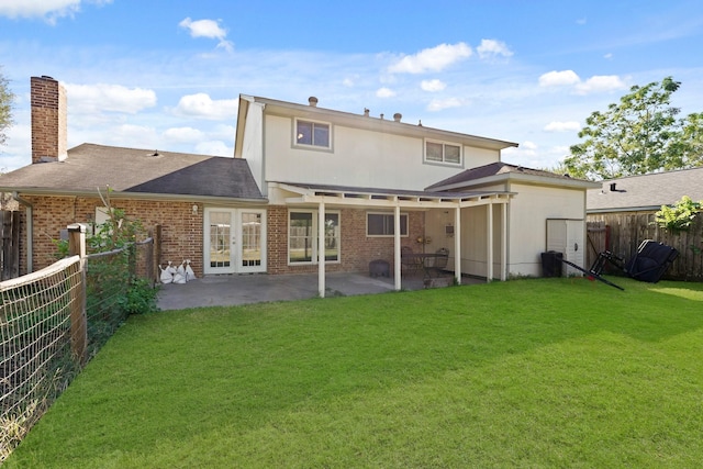 rear view of property featuring a yard, a patio, and french doors