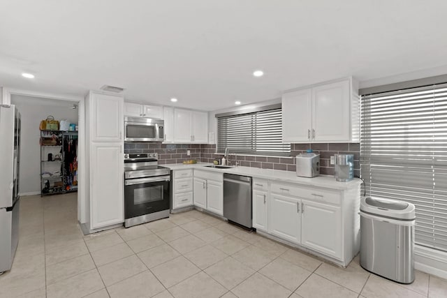 kitchen featuring sink, decorative backsplash, light tile patterned floors, white cabinetry, and stainless steel appliances