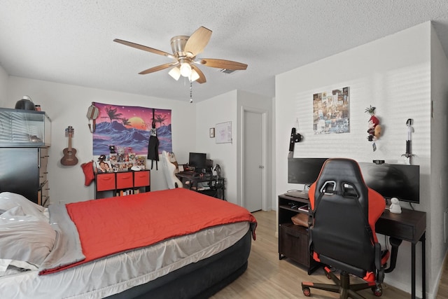 bedroom with ceiling fan, light hardwood / wood-style floors, and a textured ceiling