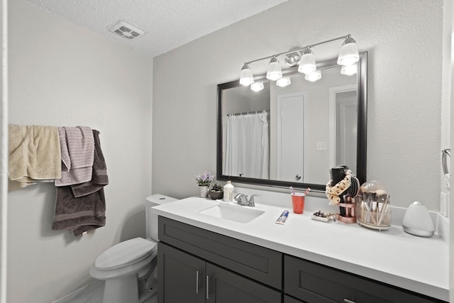 bathroom featuring vanity, a textured ceiling, and toilet