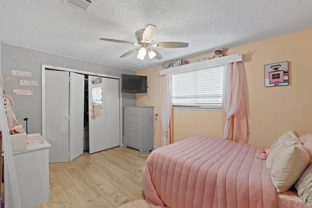 bedroom with a closet, ceiling fan, light hardwood / wood-style flooring, and a textured ceiling