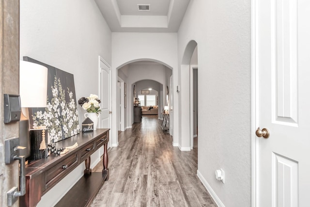 hallway featuring a raised ceiling and light wood-type flooring