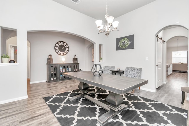 dining space with wood-type flooring and an inviting chandelier