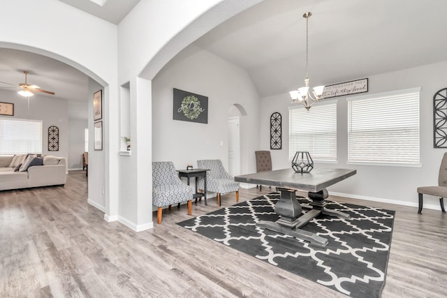 dining space featuring ceiling fan with notable chandelier, hardwood / wood-style flooring, and lofted ceiling