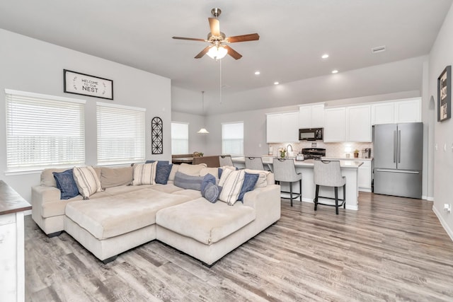 living room with plenty of natural light, ceiling fan, and light hardwood / wood-style flooring