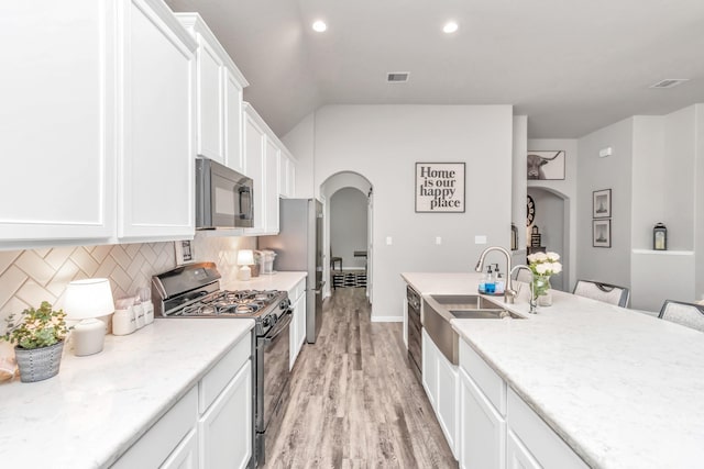 kitchen featuring light stone countertops, black gas stove, light wood-type flooring, and white cabinetry