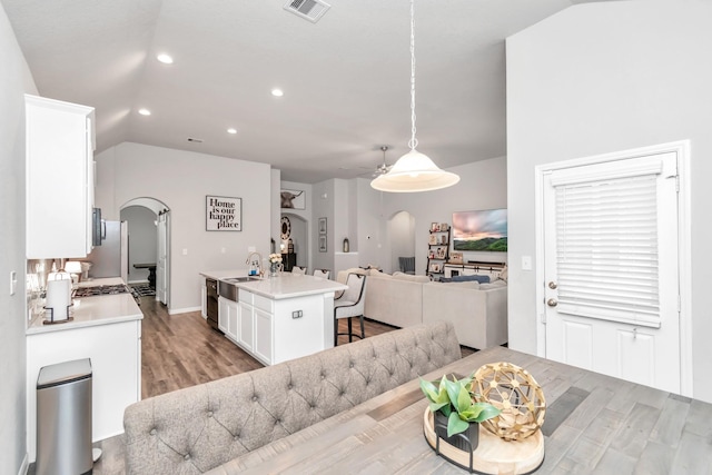 dining space featuring ceiling fan, light hardwood / wood-style floors, sink, and vaulted ceiling